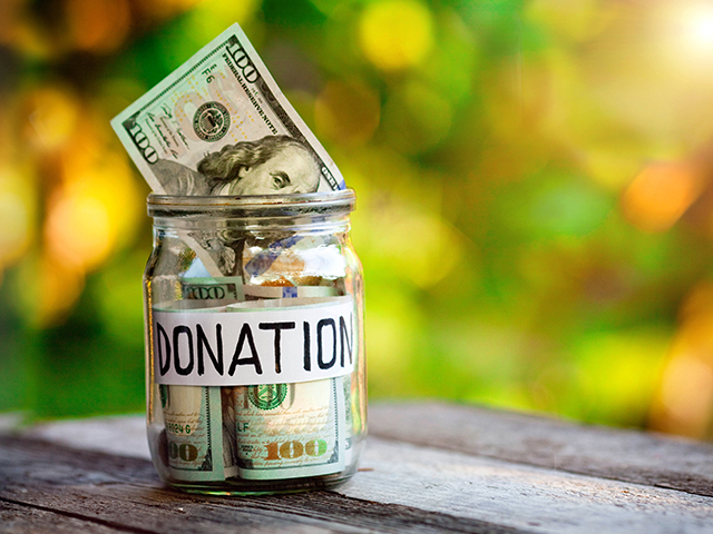 Glass jar full of money. It has a white label that reads "donations" written in black marker